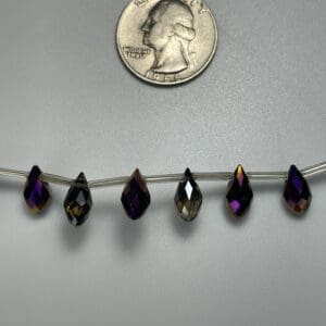 Six iridescent teardrop beads on wire.