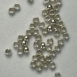 Small silver beads scattered on white surface.