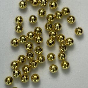 Gold beads scattered on white background.