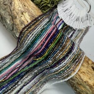 Colorful beads draped over wooden log.