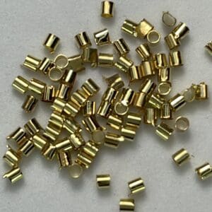 Gold crimp beads scattered on white background.