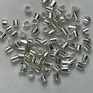 Silver crimp beads scattered on white background.