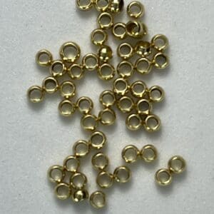 Small gold beads scattered on white surface.