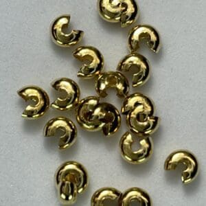 Gold-colored crimp covers on white background.