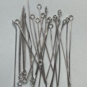 Silver metal eye pins on a surface.