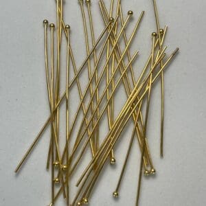 Gold headpins scattered on white surface.