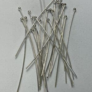 Silver headpins scattered on a white background.