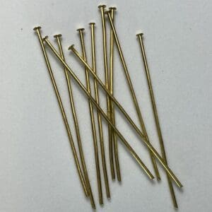 Gold metal pins scattered on white background.
