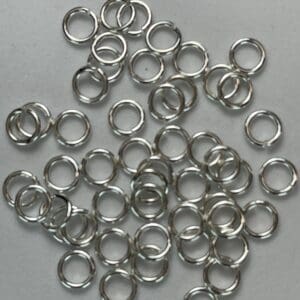 Small silver jump rings on gray paper