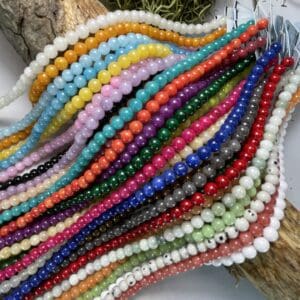 Colorful strands of beads on wooden surface.