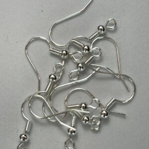 Silver earring hooks on a gray surface.