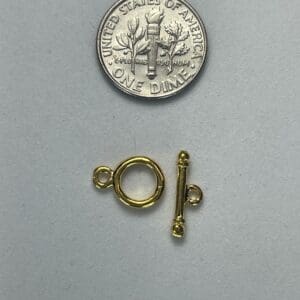 Gold toggle clasp and a dime.