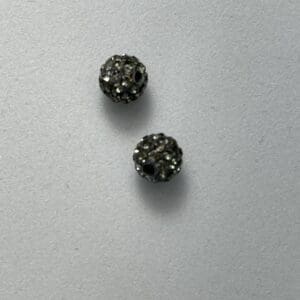 Two sparkly black beads on gray background.