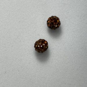 Two small brown textured beads on surface.