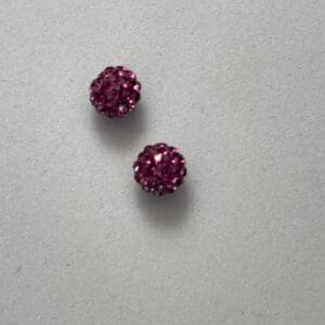 Two pink rhinestone stud earrings on display.