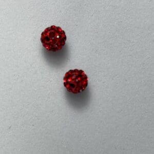 Two red sparkly beads on grey background.