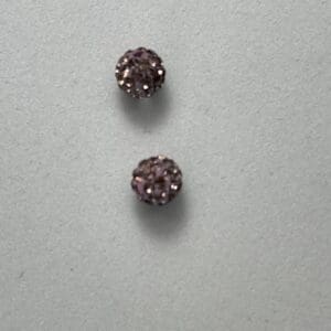 Two small purple textured beads on gray.
