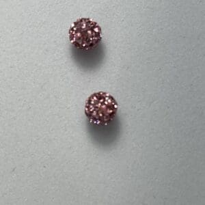 Two pink, sparkly stud earrings on display.