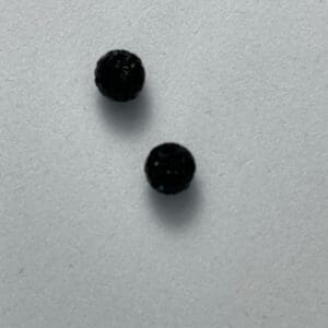 Two black round objects on grey background.