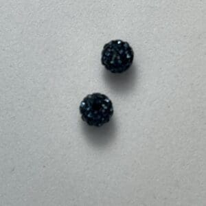 Two small textured black spheres on surface.