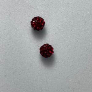 Two small round red beads on surface.