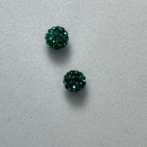 Two small green textured spheres on surface.