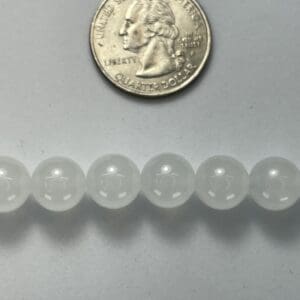 White beads beside a quarter for scale.