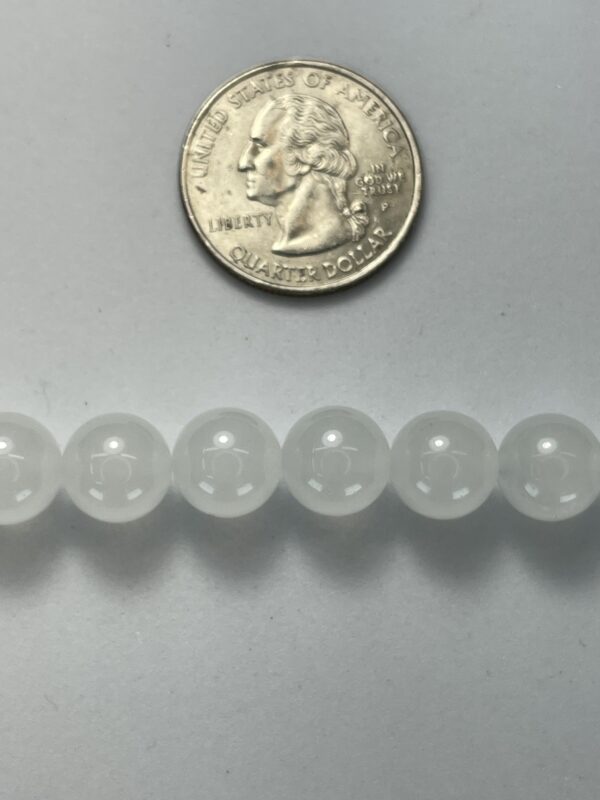 White beads beside a quarter for scale.