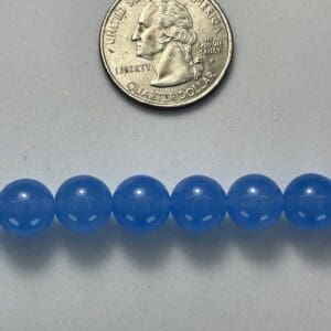 Light blue gemstone beads with quarter for scale.