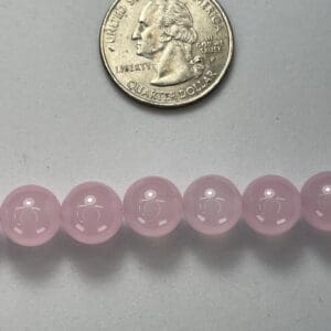 Pink rose quartz beads with quarter for scale.