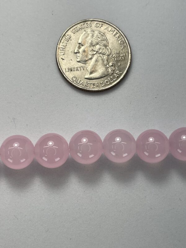 Pink rose quartz beads with quarter for scale.