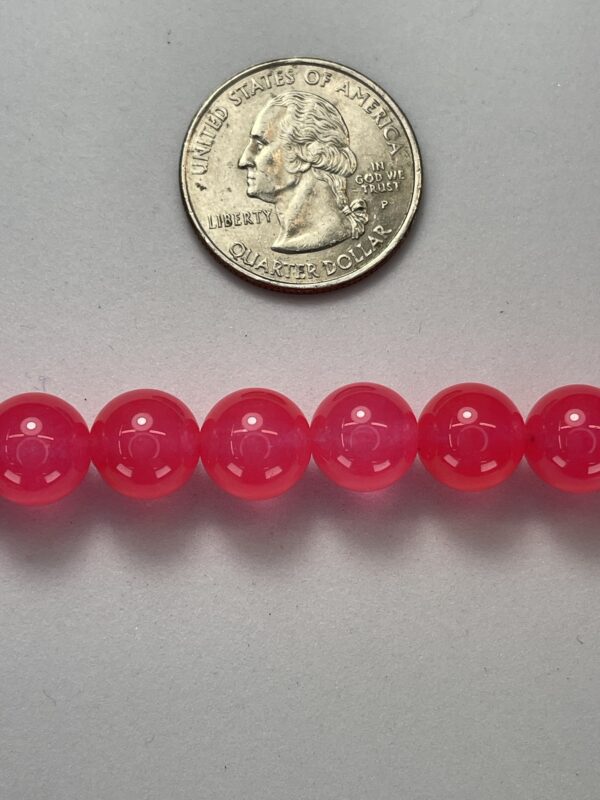 Pink gemstone beads with quarter for scale.