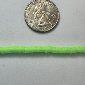 Neon lime disc beads beside quarter