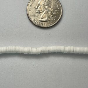 Quarter coin beside small white beads.