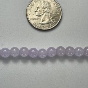 Lavender beads next to a quarter.
