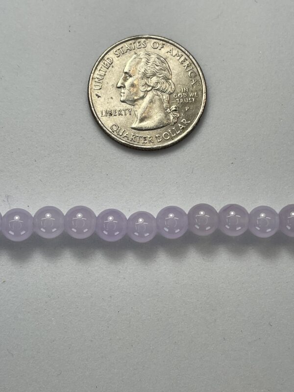 Lavender beads next to a quarter.