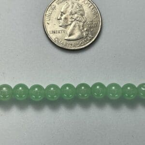 Light green beads next to quarter.