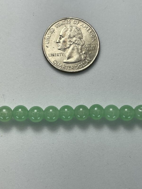 Light green beads next to quarter.