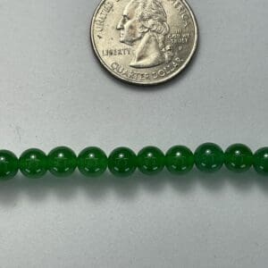 Green jade beads with quarter for scale.