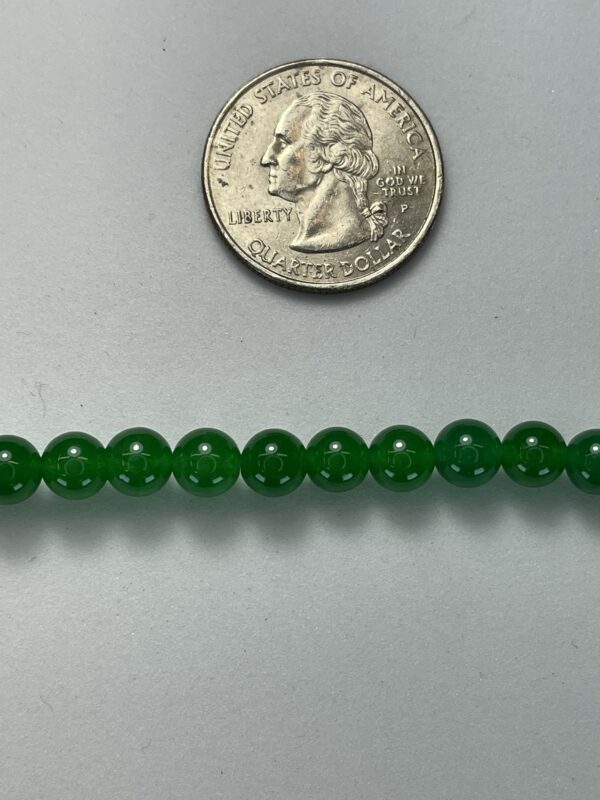 Green jade beads with quarter for scale.