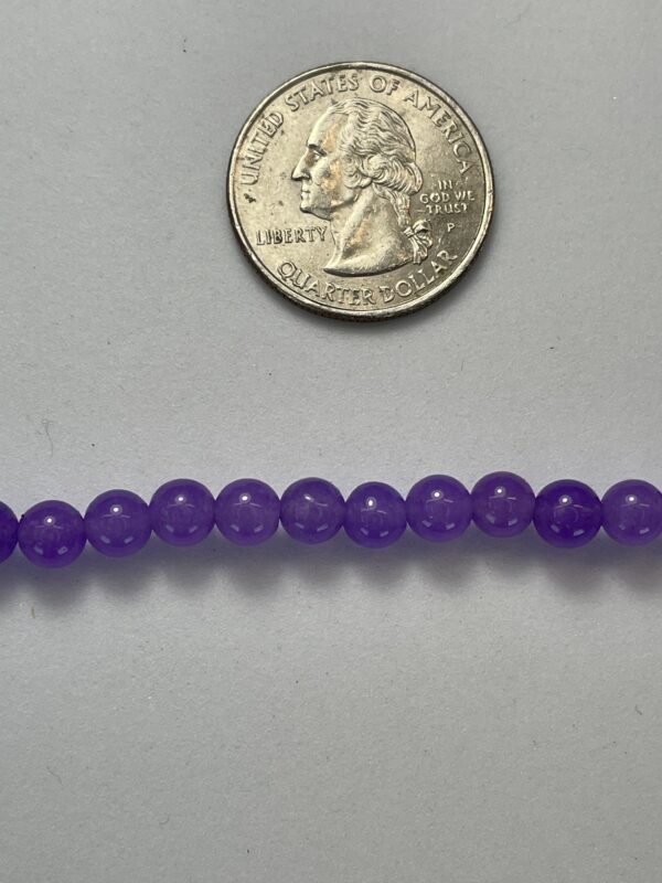 Purple beads next to a quarter.