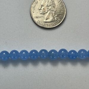 Light blue round beads with quarter for scale.
