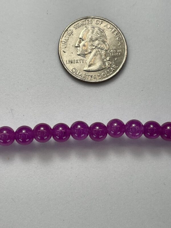 Purple beads next to a quarter.