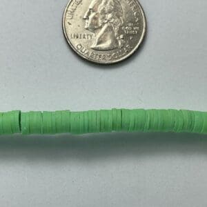 Quarter coin and green beads on surface.