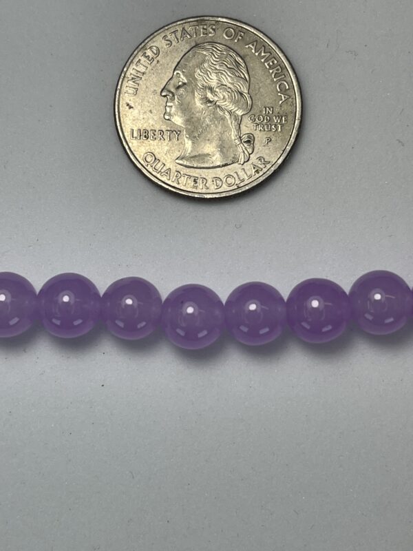 Purple beads next to a quarter.
