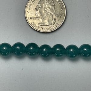 Dark green beads next to quarter.