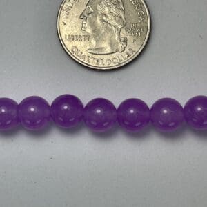 Purple beads next to a quarter.