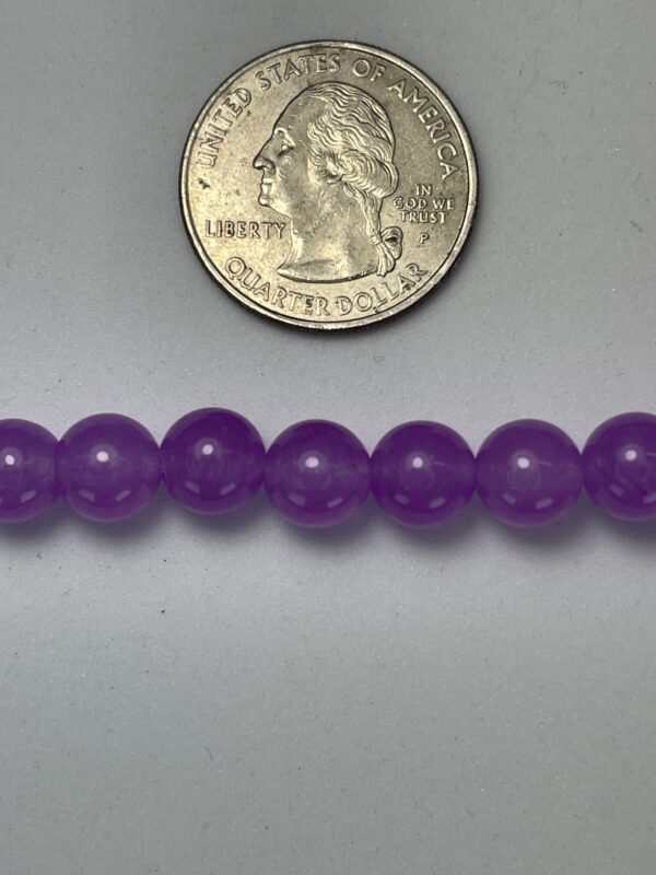 Purple beads next to a quarter.