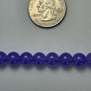 Purple beads next to a quarter.