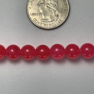 Pink round beads with quarter for scale.
